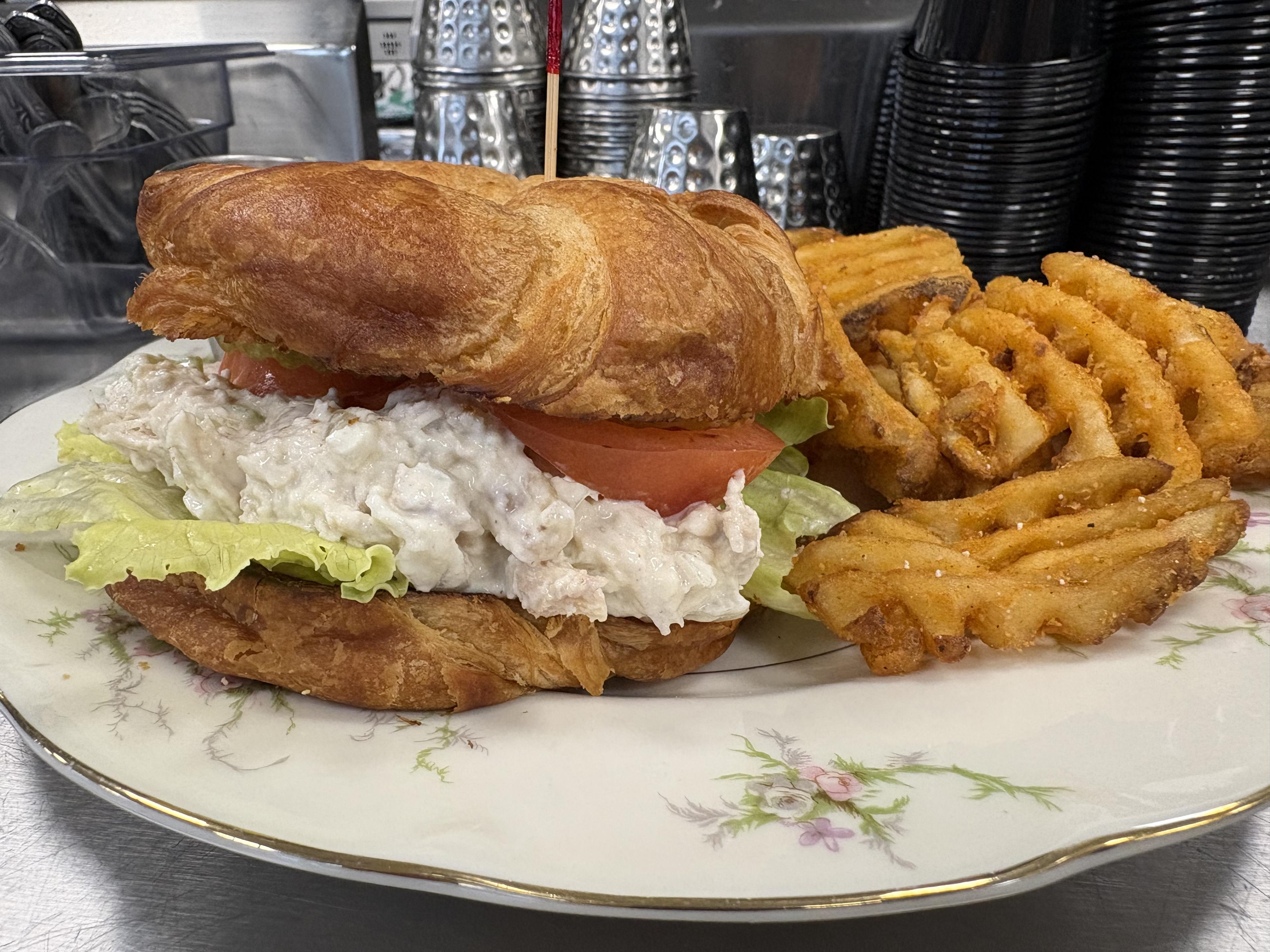 A chicken salad croissant sandwich with waffle fries at Fairways at GLC
